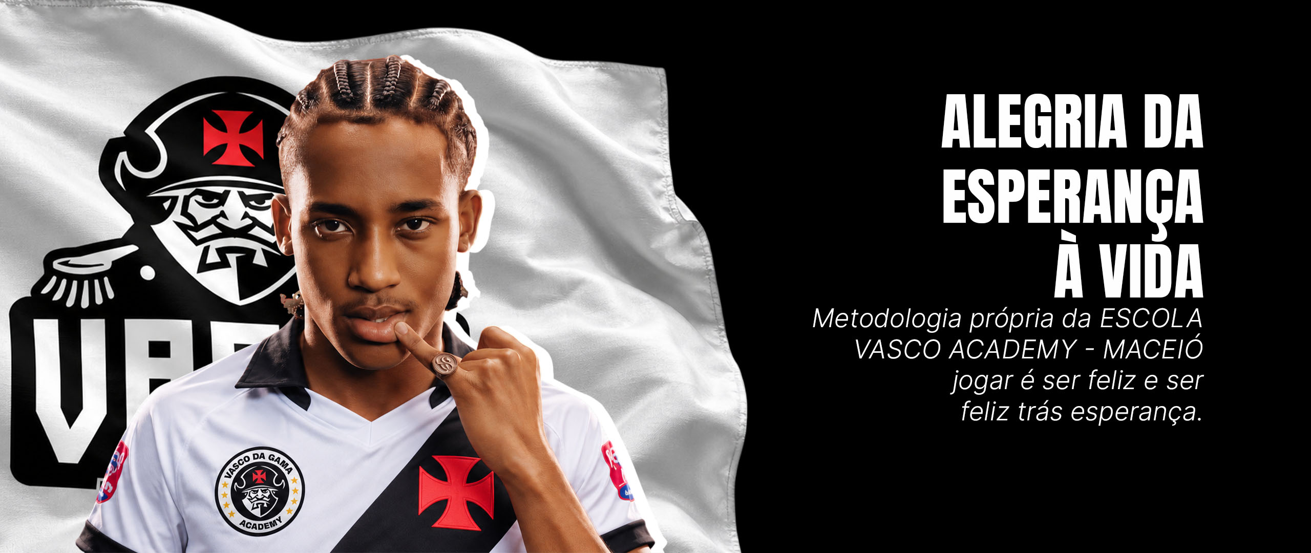 Atleta com a camisa branca e faixa preta da Vasco Academy em frente à bandeira da escola